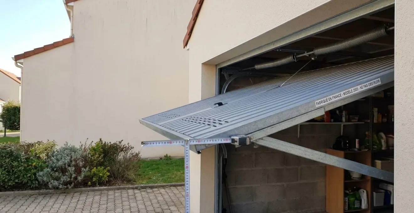 Porte de garage basculante débordante en acier galvanisé en position ouverte, vue latérale montrant le débordement extérieur de 30-40 cm caractéristique de ce système d'ouverture